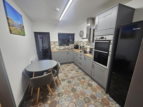 a kitchen with a table and a black refrigerator at cosy cottage in snowdonia in Brynkir