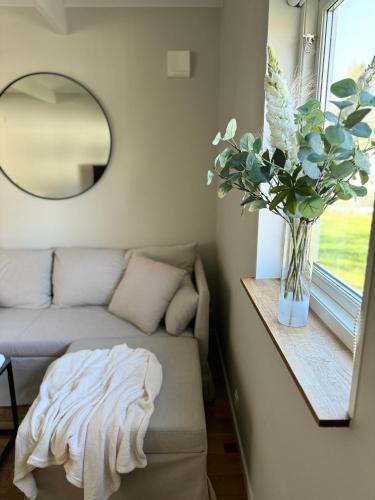una sala de estar con sofá y un jarrón de flores en Holiday house in nature-filled Vidja, near Stockholm City, en Farsta