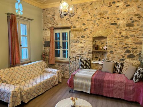 a living room with a couch and a stone wall at Irene's Mansion in Vrontádos