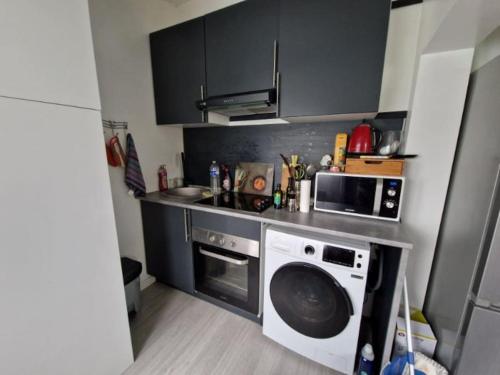 une cuisine avec un lave-linge et un micro-ondes dans l'établissement charmante maisonnette, à Mitry-Mory