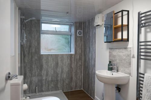 bagno con lavandino, servizi igienici e finestra di Garden Apartment by Kahuna Stays 