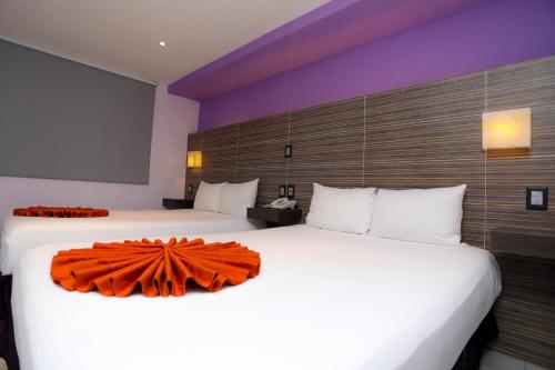 two beds in a hotel room with an orange bow on them at Hotel Kavia in Cancún