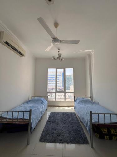 een slaapkamer met 2 bedden en een plafondventilator bij Blue Umbrella in Muscat