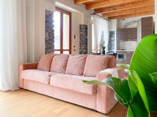 un sofá rosa en la sala de estar con cocina en Villa Luminosa Laglio - Private Parking, Garden, en Laglio