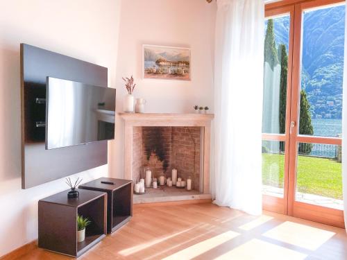 a living room with a fireplace and a television at Villa Luminosa Laglio - Private Parking, Garden in Laglio