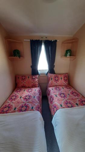 Cette petite chambre comprend 2 lits et une fenêtre. dans l'établissement 7 Lakes Country Park, 38 Sunset View, à Crowle