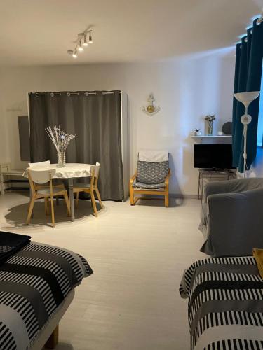 a living room with a table and chairs and a piano at Studio La source in Rochefort