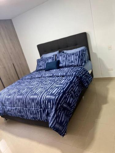 ein Bett mit blauer Bettdecke und Kissen im Schlafzimmer in der Unterkunft acogedor apartamento zona este barquisimeto in Santa Elena