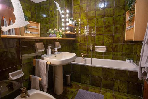 Baño de azulejos verdes con lavabo y bañera en La Casa di Carmen, en Tarvisio
