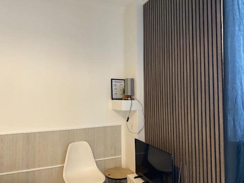 Habitación con silla blanca y TV. en Modern studio - Le Bourget Ideal JO 2024 en Le Bourget