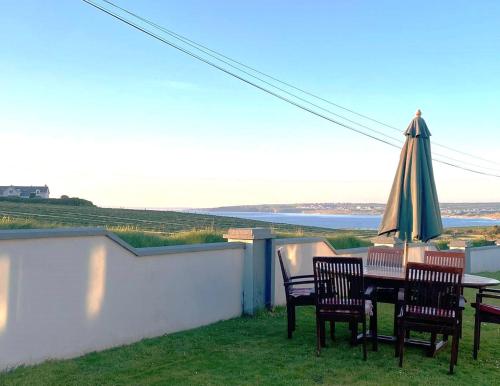 a table and chairs with an umbrella on a balcony at Kilmore Beach Apartment in Tralee