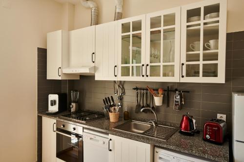 a kitchen with white cabinets and a sink at The Sunset Hideout in Lisbon