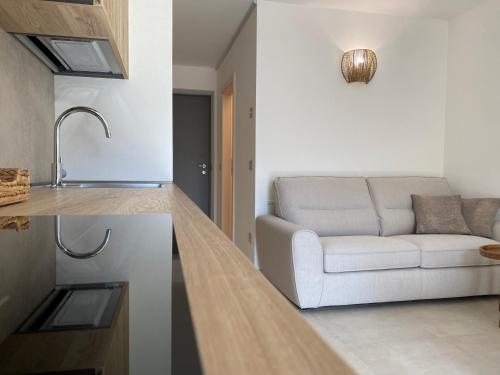 a living room with a white couch and a kitchen at Casa di Maggie 1 - Comfort e natura tra Pinzolo e Campiglio in Carisolo