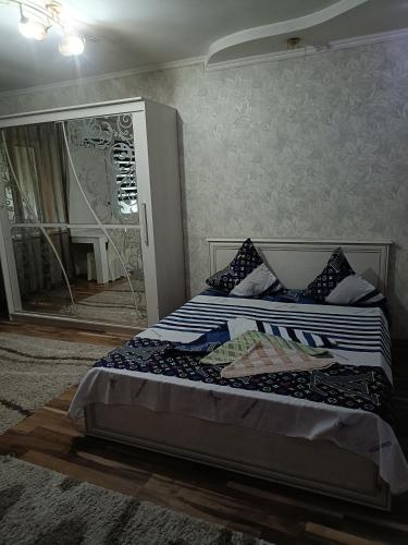 een slaapkamer met een groot bed en een spiegel bij Квартира in Taraz