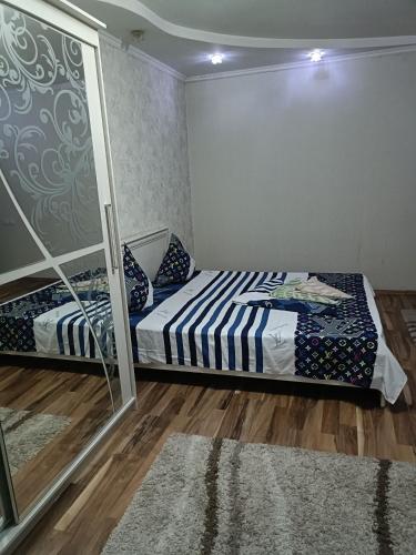 een slaapkamer met een bed en een spiegel bij Квартира in Taraz