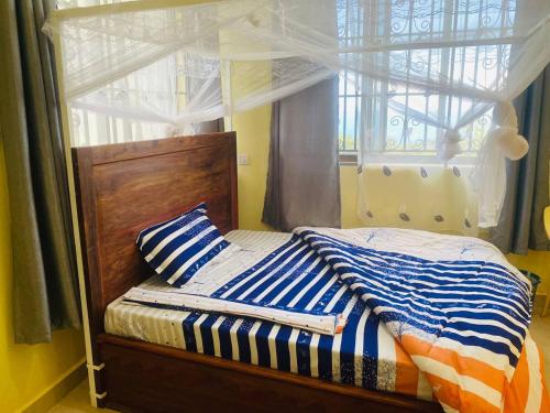1 dormitorio con 1 cama y ventana en St Paul's Hostels Buhabugali Kigoma, en Kigoma