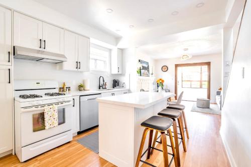 a white kitchen with white appliances and stools at 3BR Luxury Home - Heart of St Clair West in Toronto