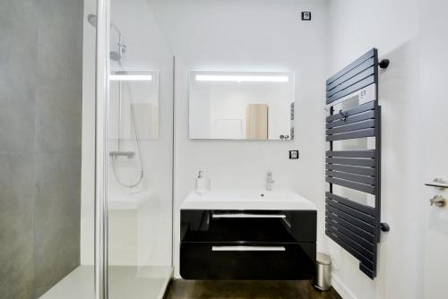 une salle de bain avec un lavabo et une douche dans l'établissement Le Versailles de Nancy, à Nancy