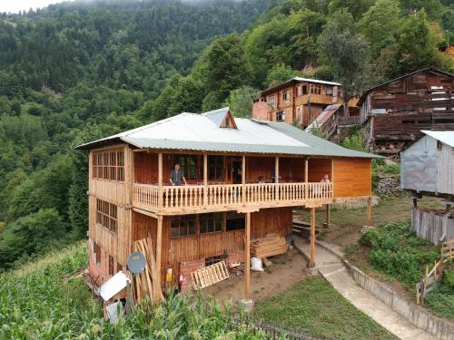 un hombre parado en el balcón de una casa de madera en Dedaena Pansiyon, en Artvin