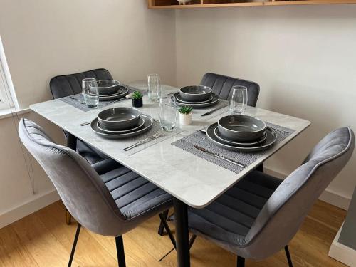 a table with chairs and plates and glasses on it at Duplex Apartment in Greater Manchester in Oldham