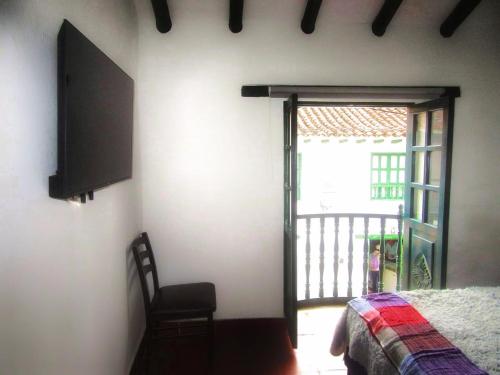 um quarto com uma televisão, uma cama e uma janela em Carazo chef Host & Food em Villa de Leyva
