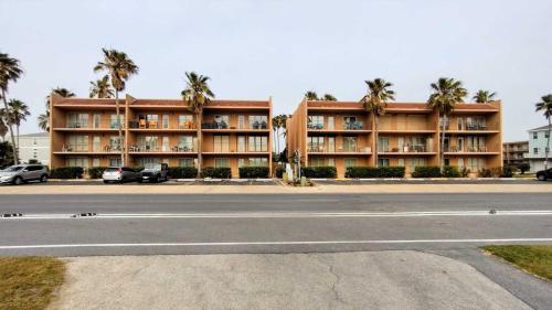 a building with palm trees in front of a street at Beachview 105 Condominium Condo in South Padre Island