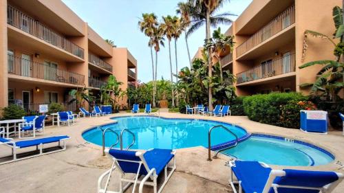 una piscina en un complejo con sillas azules y palmeras en Beachview 105 Condominium Condo, en South Padre Island
