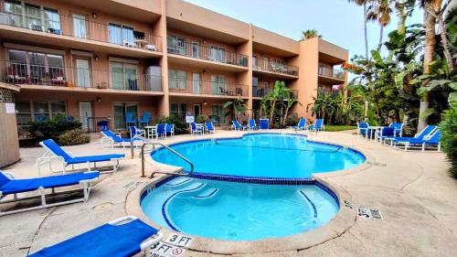 una piscina frente a un hotel con tumbonas azules en Beachview 105 Condominium Condo, en South Padre Island