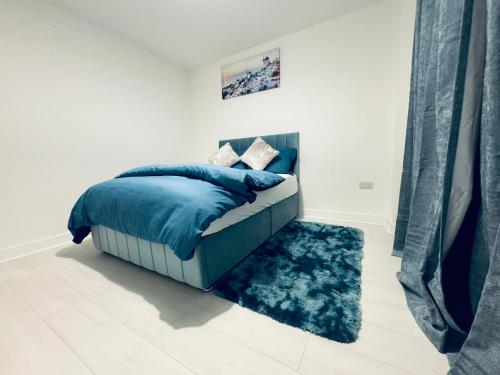 sypialnia z łóżkiem z niebieską pościelą i niebieskim dywanem w obiekcie Potter Service Accomodation w mieście Aldershot