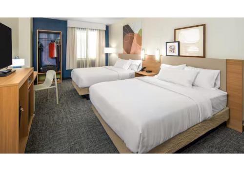 a hotel room with two beds and a desk at Spark by Hilton Shepherdsville Louisville South in Shepherdsville