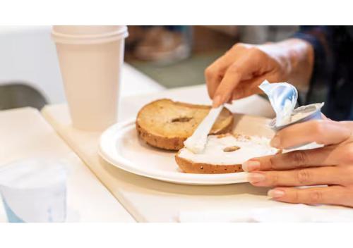 une personne mangeant un morceau de pain sur une assiette dans l'établissement Spark by Hilton Shepherdsville Louisville South, à Shepherdsville