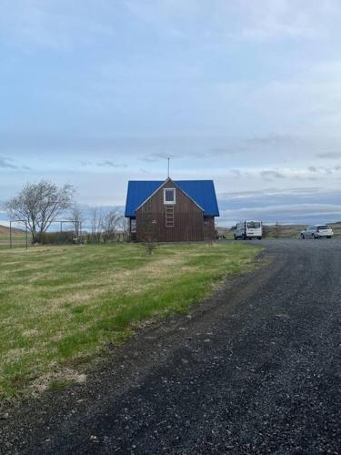 a barn with a blue roof on the side of a road at Black Valley apartment in Þóroddsstaðir