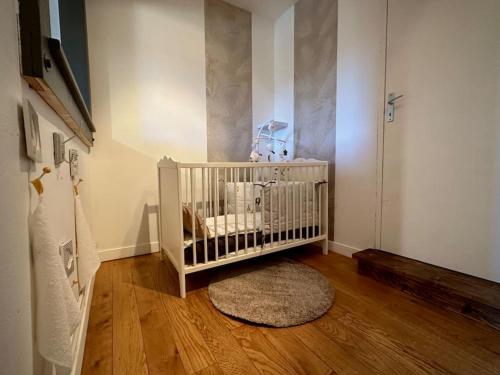 a baby crib in a room with a wooden floor at Le gîte du besson Cassagne in Cassagne
