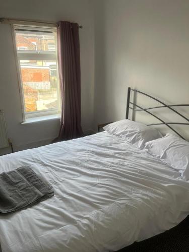 Cosy Widnes Home في ويدنز: سرير أبيض في غرفة نوم مع نافذة