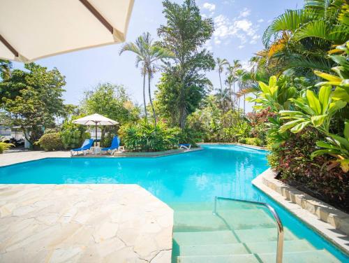 a swimming pool in a resort with palm trees at 2br Caribbean Condo In Cabarete Center in Cabarete