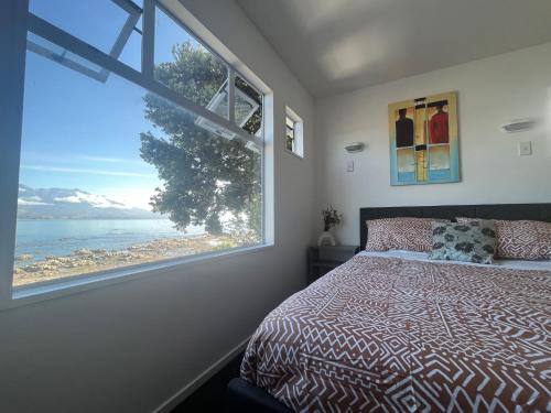 カイコウラにあるKaikoura Seaside lodgeのベッドルーム1室(ベッド1台、大きな窓付)