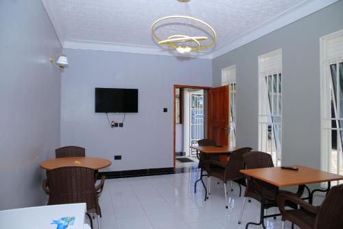 una sala da pranzo con tavoli, sedie e TV a schermo piatto di JOSELLA MOTEL MUBENDE a Mubende