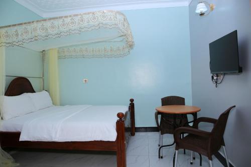 1 dormitorio con cama, mesa y TV en JOSELLA MOTEL MUBENDE, en Mubende