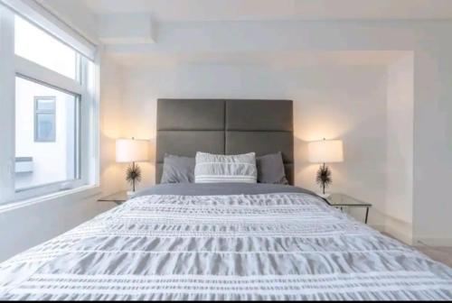 卡爾加里的住宿－City Escape Oasis，白色卧室配有一张带两盏灯的大床
