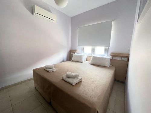 1 dormitorio con 1 cama con toallas en Topikos Apartments, en Ayia Napa