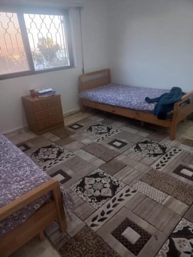 una camera con due letti e un tappeto sul pavimento di شقق ايلين 