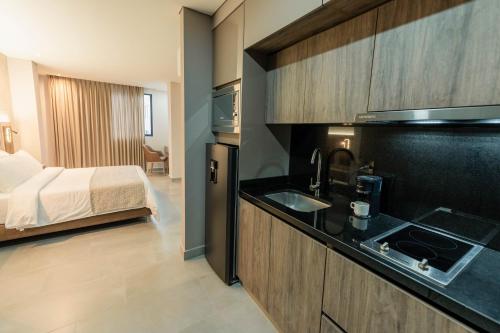 una cocina con fregadero y una cama en una habitación en Amari Living Suites, en Barranquilla