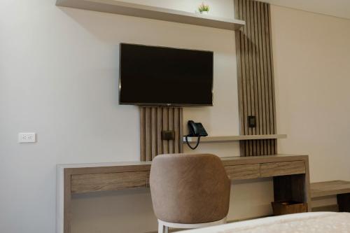 a room with a chair and a television on a wall at Amari Living Suites in Barranquilla