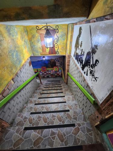a staircase in a building with paintings on the walls at Hotel Atenas Jericó in Jericó