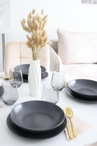 a table with black plates and glasses and a vase at Alice Apartament in Gliwice