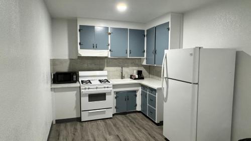 a kitchen with blue cabinets and a white refrigerator at Hitching Post Studios Inn in Santa Cruz