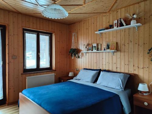 1 dormitorio con 1 cama azul y paredes de madera en Haisle im Untrborkh, en Sauris