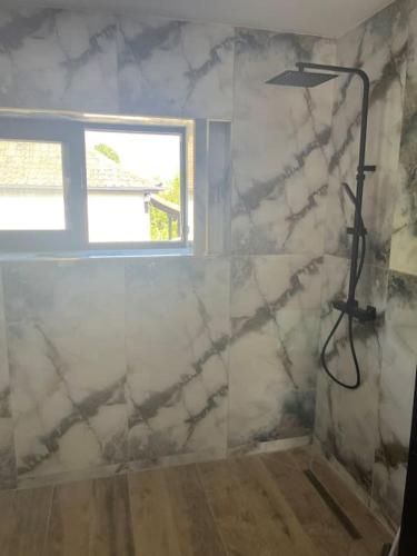 La salle de bains est pourvue d'une douche et d'une fenêtre. dans l'établissement Maison paisible cadre agréable avec spa privatisé, à Lutterbach