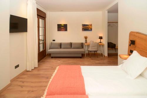 A Reigada Hotel Restaurante في غرانداس دي ساليمي: غرفة نوم بسرير واريكة وطاولة