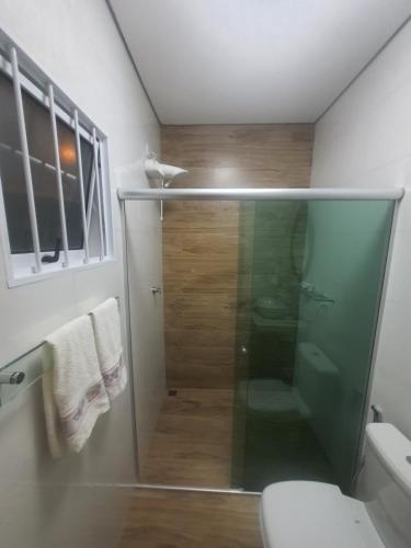 uma casa de banho com uma cabina de duche em vidro e um WC. em Recanto Das Borboletas em São Roque